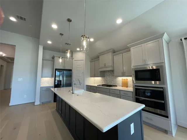 a kitchen with kitchen island a sink appliances and a counter top space