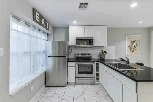 a kitchen with a sink a refrigerator and a stove top oven with wooden cabinets