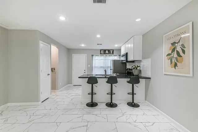 a kitchen with stainless steel appliances kitchen island granite countertop a refrigerator and white cabinets