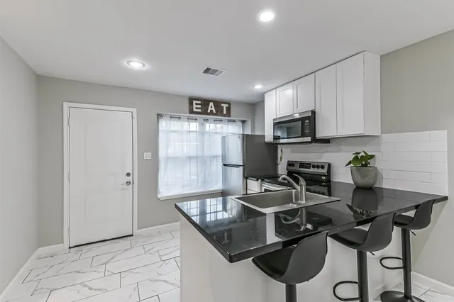 a kitchen with a table chairs refrigerator and microwave