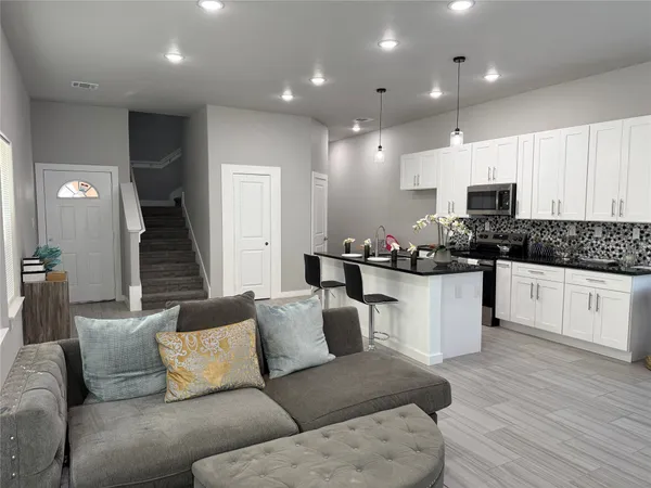 a living room with furniture kitchen view and a potted plant