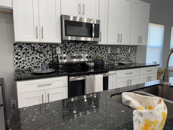 a kitchen with a sink and a stove with white cabinets