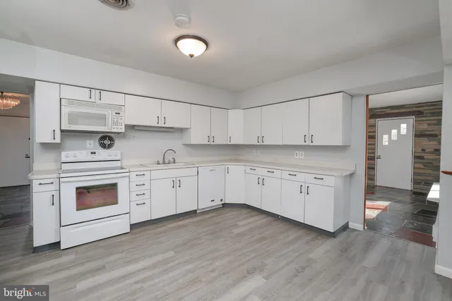 a kitchen with stainless steel appliances white cabinets and wooden floors