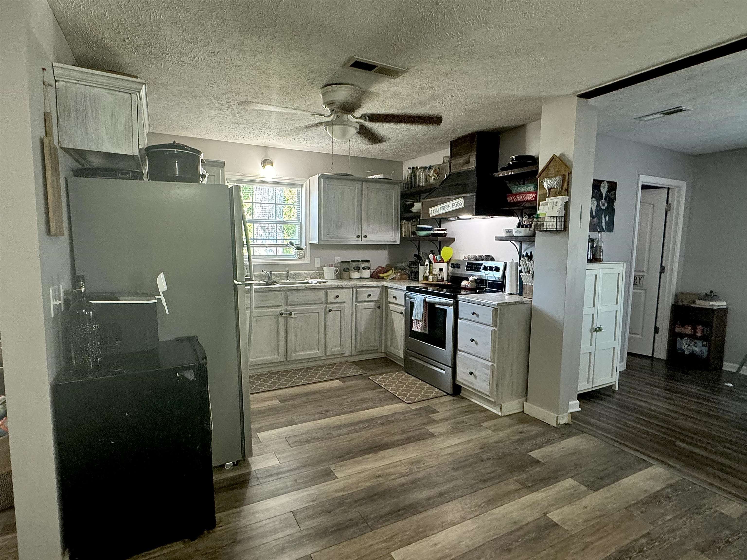 780 Ammons Road Selmer, TN 38375 - Photo 4 of 21 Kitchen with appliances with stainless steel finishes, a textured ceiling, ceiling fan, wood-type flooring, and range hood
