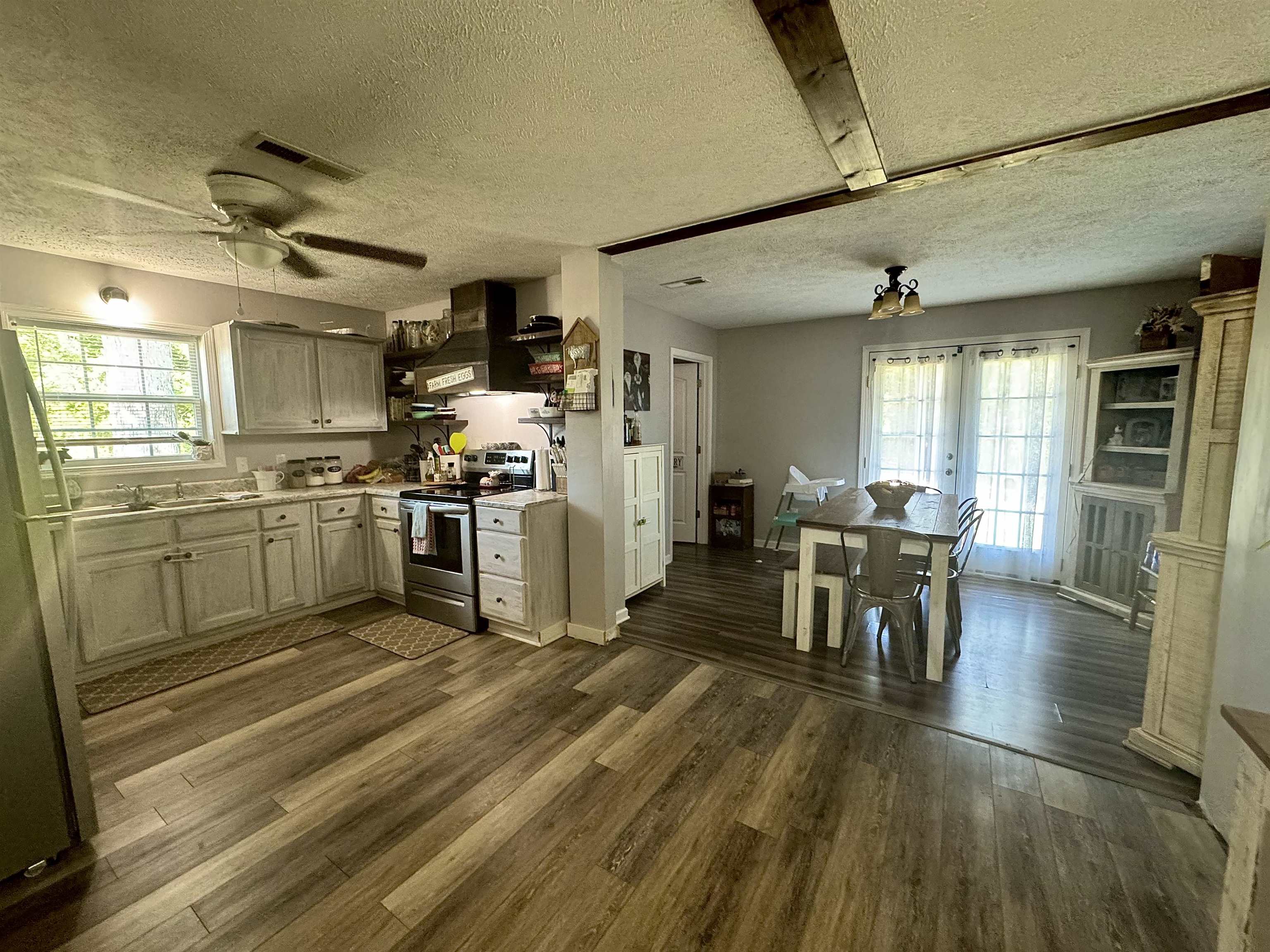 780 Ammons Road Selmer, TN 38375 - Photo 5 of 21 Kitchen with appliances with stainless steel finishes, hardwood / wood-style floors, wall chimney range hood, a textured ceiling, and ceiling fan