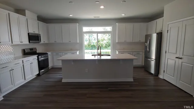 a kitchen with kitchen island wooden floors white cabinets and stainless steel appliances