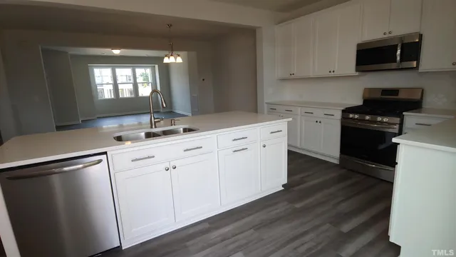 a kitchen with stainless steel appliances granite countertop a sink a stove a microwave and wooden floors