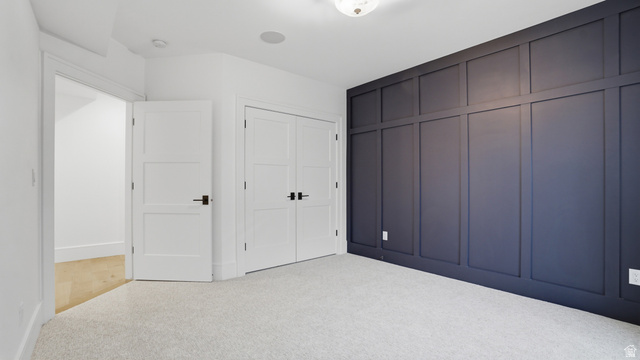 1682 North 1950 W Street, Unit 9 Provo, UT 84604 - Photo 49 of 84 Accent wall featuring dark paneling, light-colored carpet, white trim, white interior doors with black hardware, and an overhead light fixture