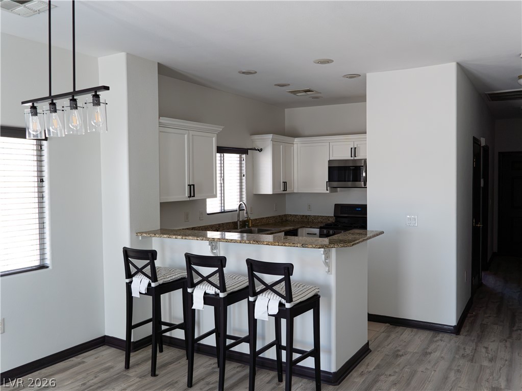 1466 Orange Jubilee Road Henderson, NV 89014 - Photo 5 of 15 A contemporary kitchen features bright white cabinetry, sleek granite countertops, and an inviting breakfast bar.