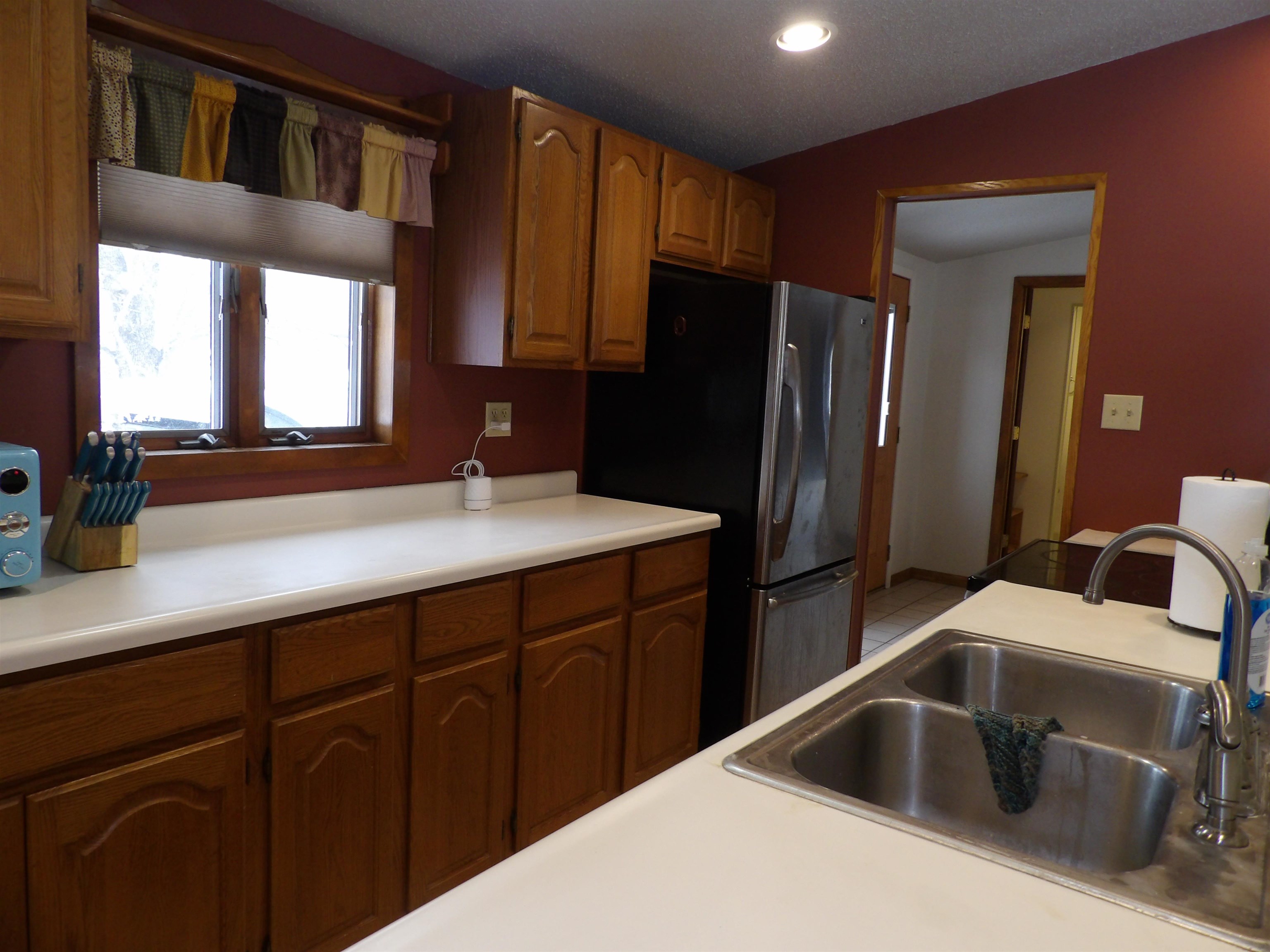 2255 Selmser Avenue Cloquet, MN 55720 - Photo 9 of 24 Kitchen with light countertops, brown cabinets, lofted ceiling, freestanding refrigerator, and recessed lighting