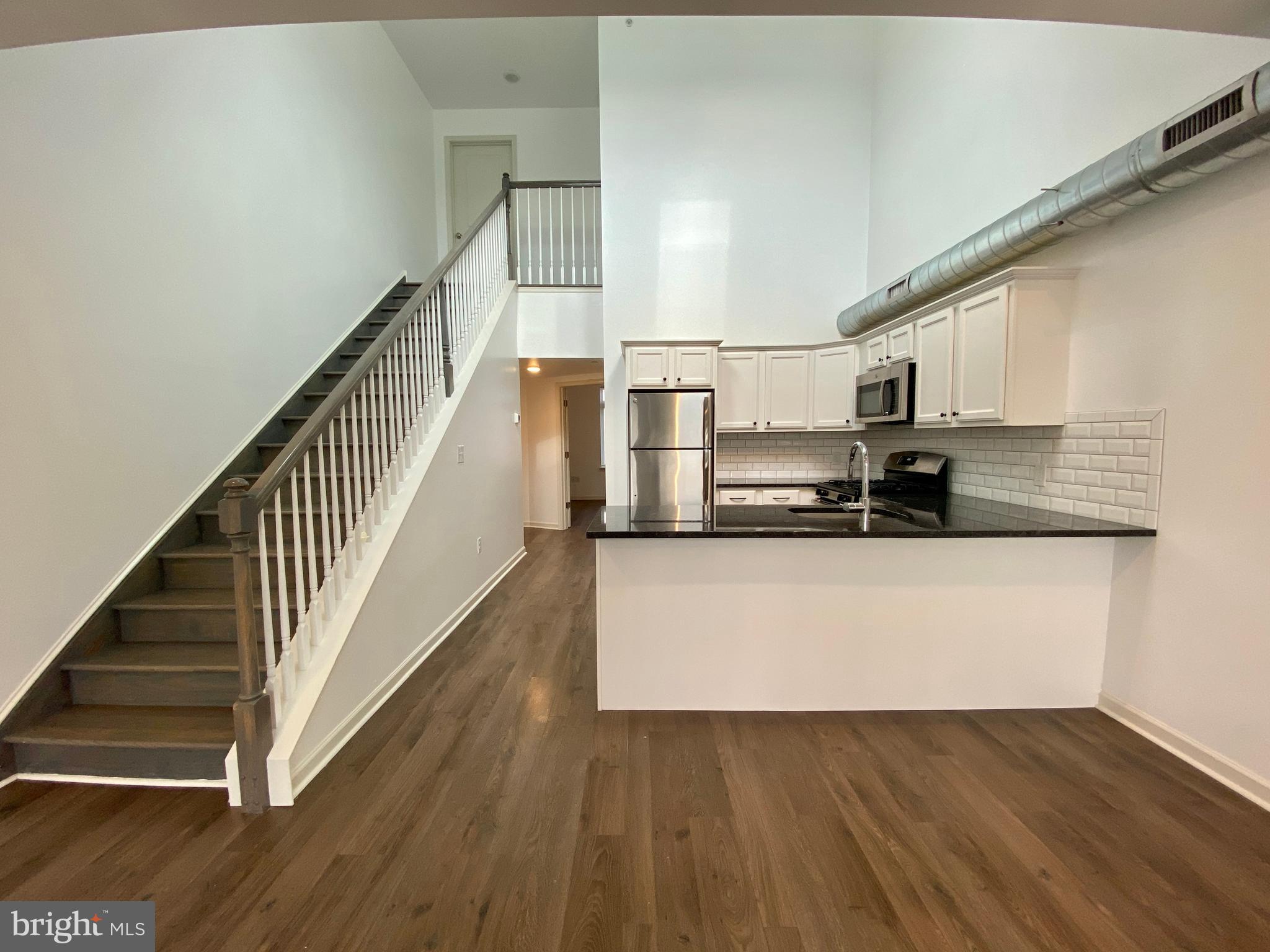 a view of a kitchen with wooden floor and stairs