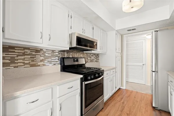 a kitchen with stainless steel appliances white cabinets and a refrigerator