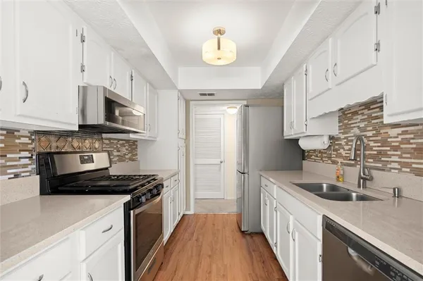 a kitchen with stainless steel appliances white cabinets and a stove top oven