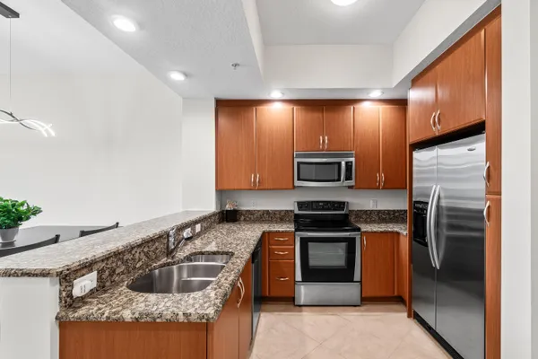 a kitchen with stainless steel appliances granite countertop a stove a sink and a microwave