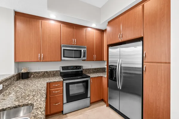 a kitchen with stainless steel appliances granite countertop a refrigerator a stove and a sink