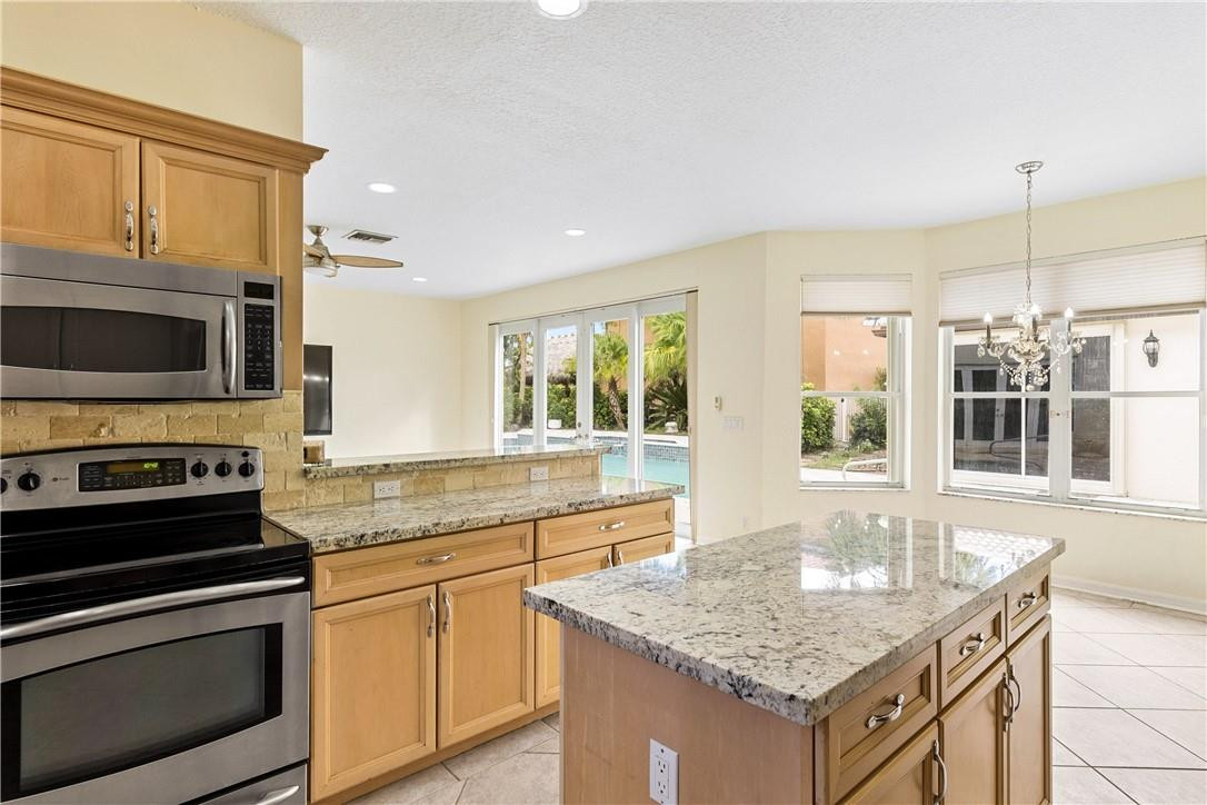 10945 Ravel Court Boca Raton, FL 33498 - Photo 12 of 24 a kitchen with stainless steel appliances granite countertop a stove a sink and a microwave