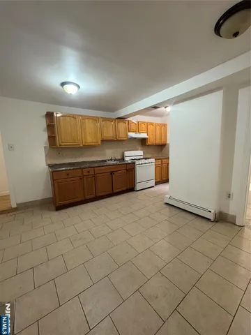 a large white kitchen with a sink and dishwasher a stove top oven with wooden floor