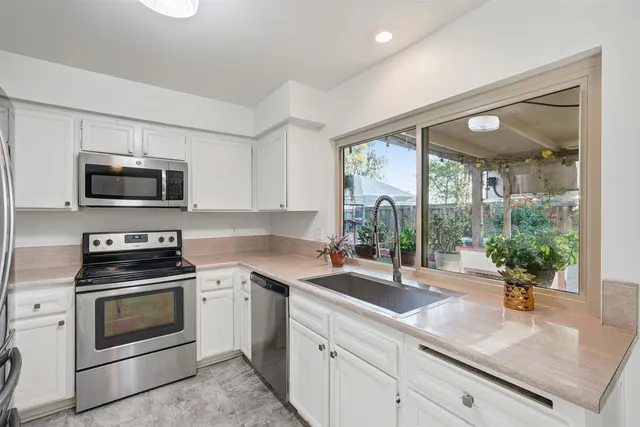 a kitchen with sink a large window and stainless steel appliances