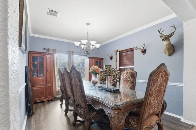 a dining room with furniture wooden floor a chandelier and a mirror