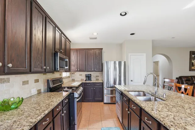 a kitchen with kitchen island granite countertop a sink stove and cabinets