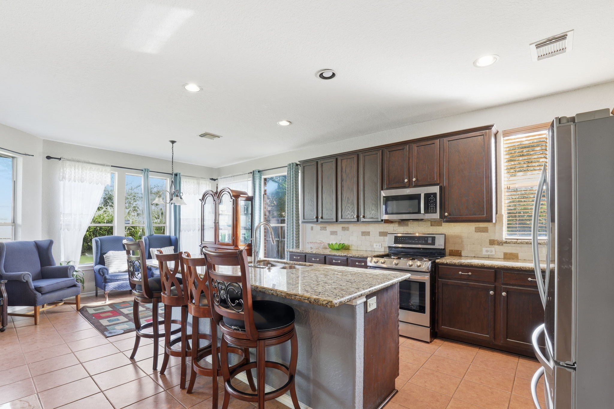 8202 Terrace Brook Drive Houston, TX 77040 - Photo 2 of 23 Bright kitchen and dining area with large windows, dark wood cabinets, stainless steel appliances, and a central island with bar seating and breakfast area