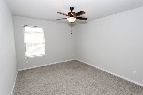 an empty room with a window and a fan