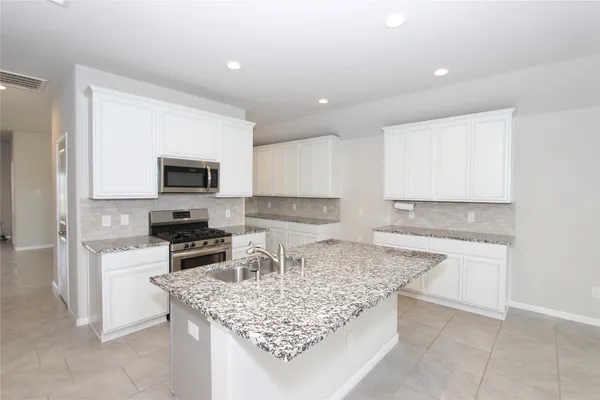 a kitchen with granite countertop a sink stove and cabinets