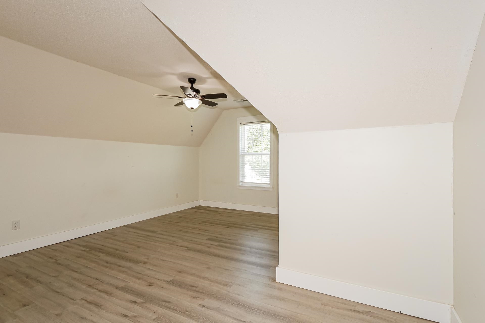 188 David Reed Drive Munford, TN 38058 - Photo 15 of 20 Spacious room featuring sloped ceilings, wood-finish flooring, a ceiling fan with integrated lighting, and a double-hung window with blinds
