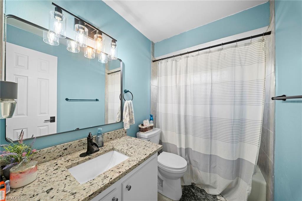 7289 Barragan Road Fort Myers, FL 33967 - Photo 14 of 18 Bathroom vanity featuring a light-colored countertop with an undermount sink, a dark-finish faucet, and a rectangular mirror