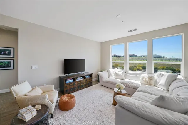a living room with furniture a flat screen tv and a large window