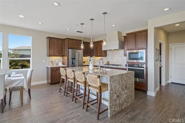 a kitchen with stainless steel appliances a dining table chairs refrigerator and sink