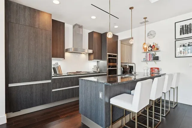 a kitchen with stainless steel appliances granite countertop a stove a refrigerator and a dining table with wooden floor