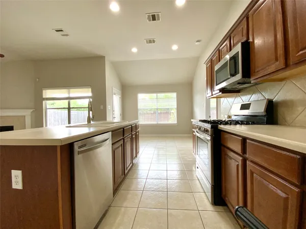 a view of a kitchen with a sink a fireplace and windows