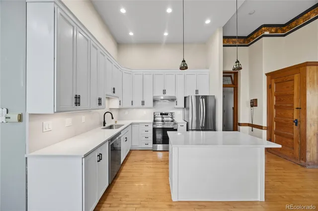 a large kitchen with stainless steel appliances granite countertop a lot of counter space and wooden floors