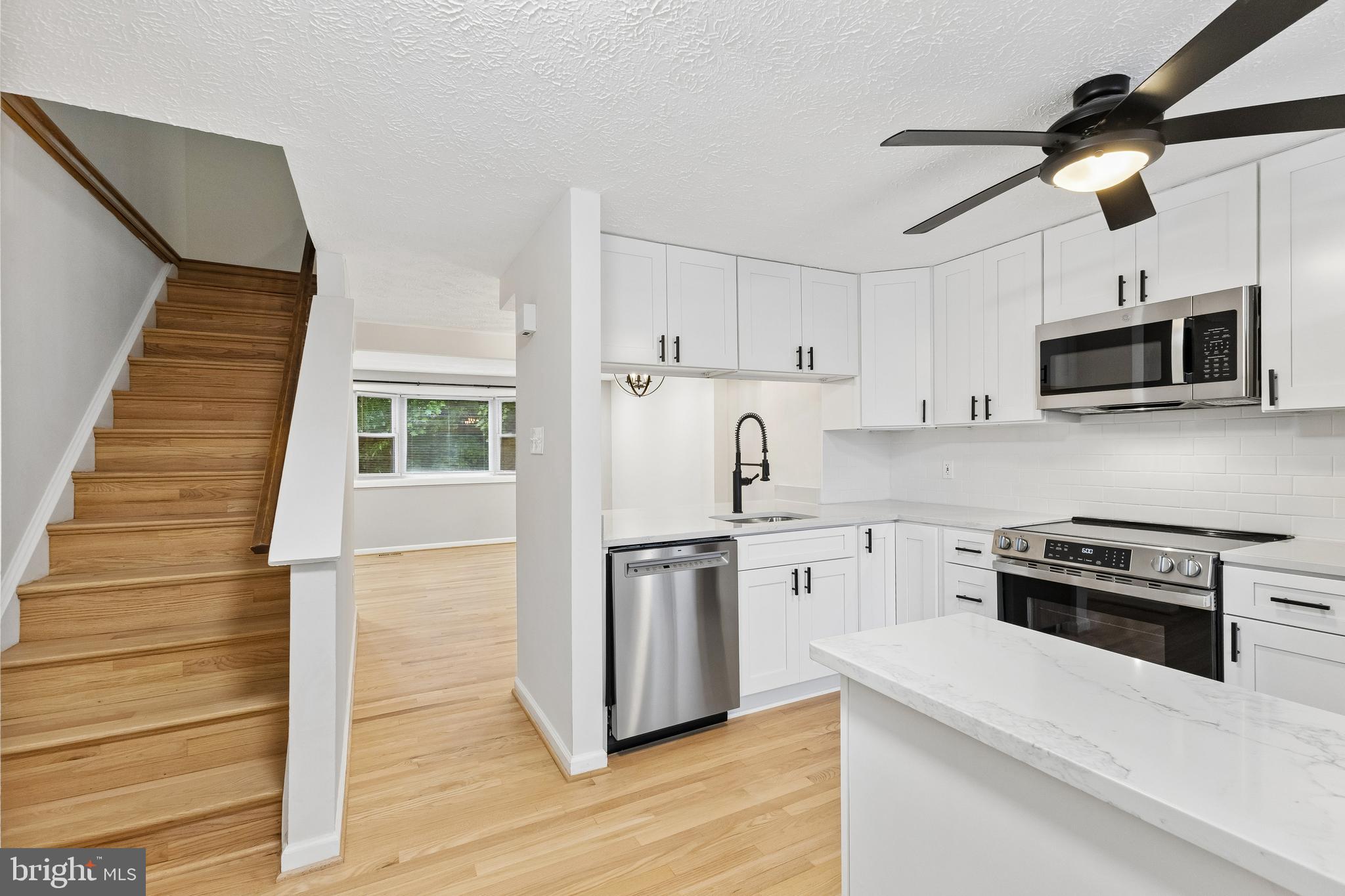 8317 Brookvale Court Springfield, VA 22153 - Photo 17 of 33 a kitchen with stainless steel appliances white cabinets a sink a stove a microwave and wooden floors