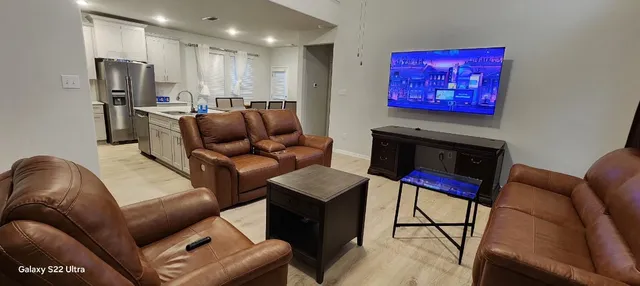 a kitchen with stainless steel appliances kitchen island granite countertop a refrigerator a stove a sink dishwasher a dining table and chairs with wooden floor