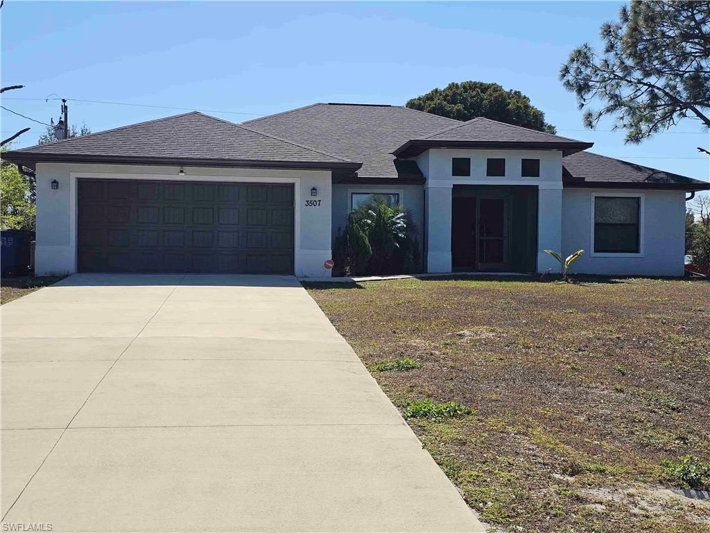 View of front of home with a shingled roof, stucco siding, driveway, and a garage