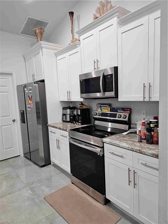3507 2nd Street Southwest Lehigh Acres, FL 33976 - Photo 17 of 27 Kitchen with stainless steel appliances, white cabinets, and light stone counters