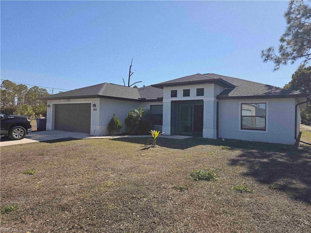 3507 2nd Street Southwest Lehigh Acres, FL 33976 - Photo 2 of 27 View of front of property featuring stucco siding, a front lawn, driveway, and a garage