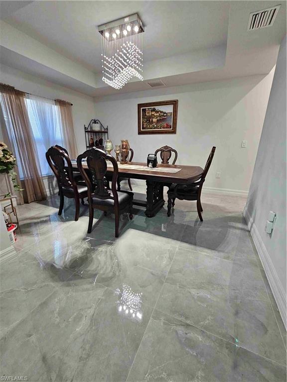 3507 2nd Street Southwest Lehigh Acres, FL 33976 - Photo 24 of 27 Dining space featuring a raised ceiling, a chandelier, and light marble finish flooring