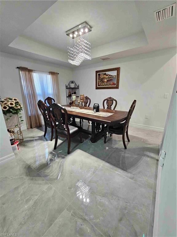 3507 2nd Street Southwest Lehigh Acres, FL 33976 - Photo 25 of 27 Dining space with a raised ceiling and a chandelier