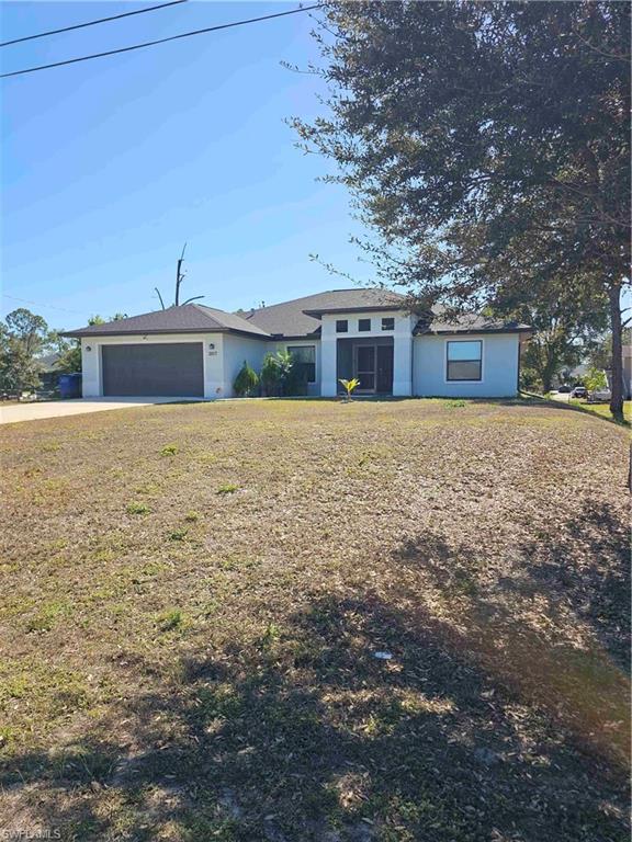 3507 2nd Street Southwest Lehigh Acres, FL 33976 - Photo 6 of 27 View of front of home featuring concrete driveway, an attached garage, a front lawn, and stucco siding