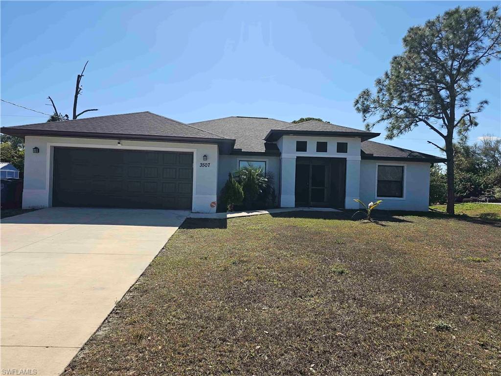 3507 2nd Street Southwest Lehigh Acres, FL 33976 - Photo 8 of 27 Prairie-style house with a front lawn, driveway, stucco siding, and a garage