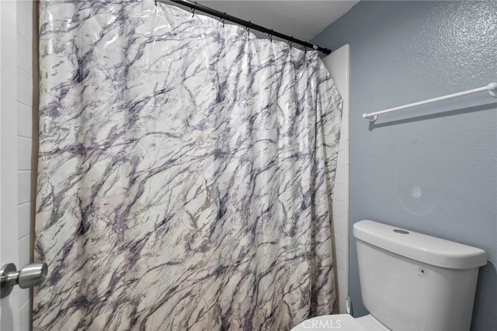 3684 North Veronica Court Rialto, CA 92377 - Photo 13 of 75 a bathroom with a toilet and a shower curtain