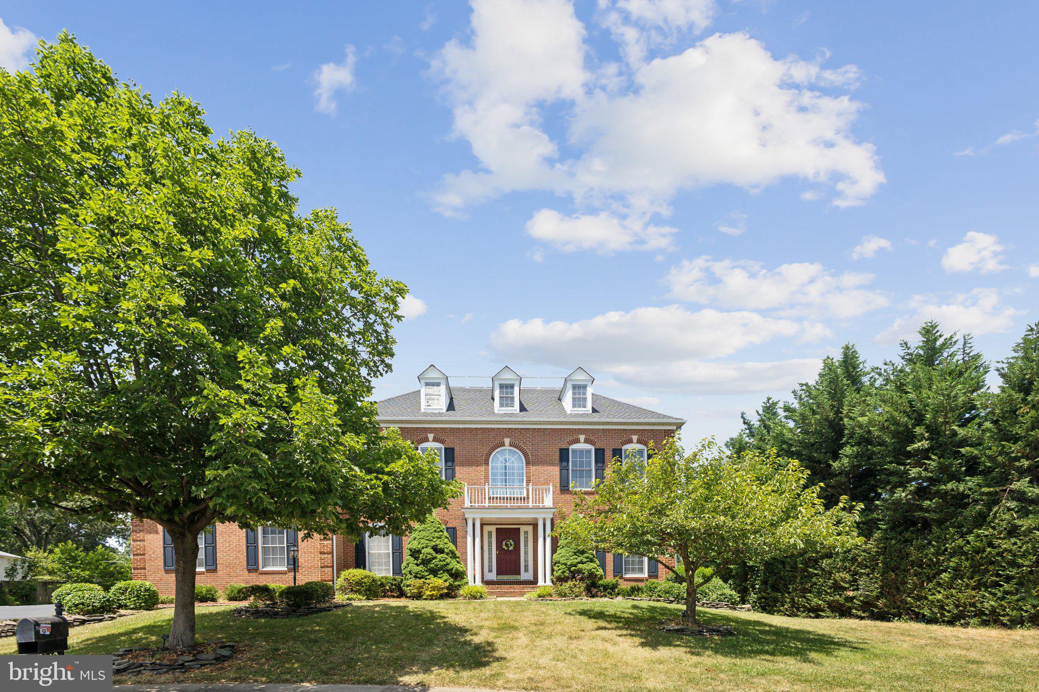 a view of a big house with a big yard and large trees