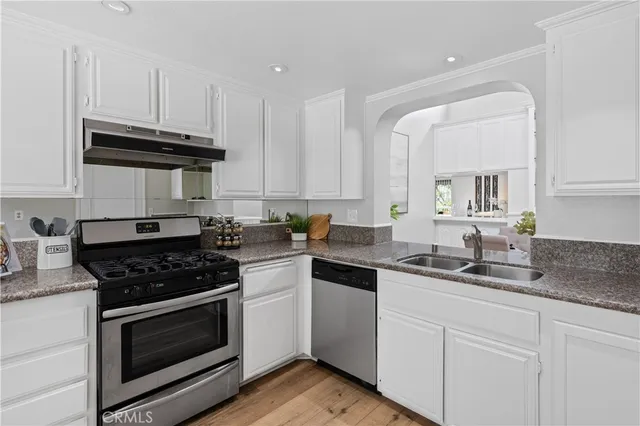 a kitchen with stainless steel appliances kitchen island granite countertop a stove a sink a refrigerator and white cabinets