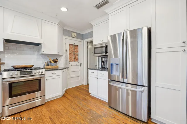 a kitchen with white cabinets and stainless steel appliances