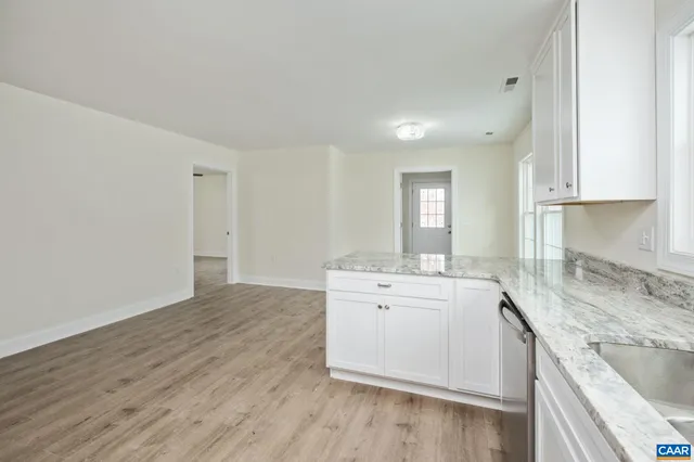 a kitchen with granite countertop white cabinets and a window