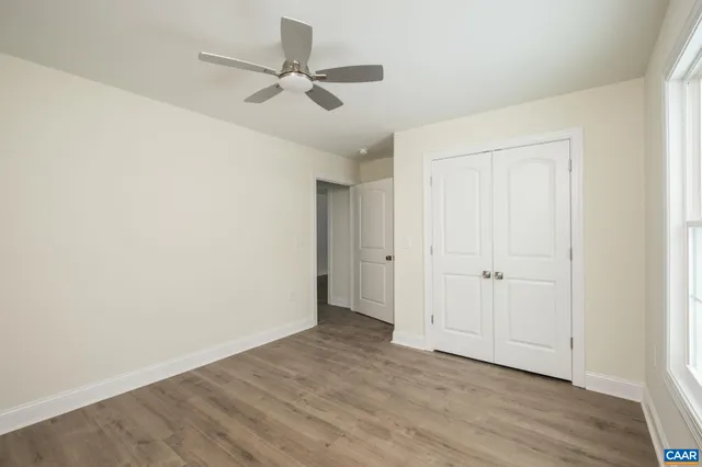 an empty room with wooden floor ceiling fan and windows