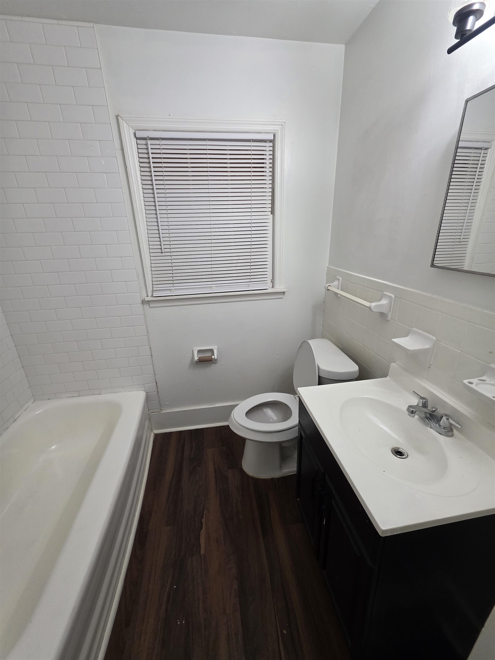 3764 Cazassa Road Memphis, TN 38116 - Photo 10 of 16 Bathroom featuring a classic white bathtub with subway tile surround, dark wood-finish flooring, and a white vanity with an integrated sink